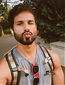 hahid Kapoor in a casual vest, flaunting his muscular biceps with a travel bag beside him.jpg